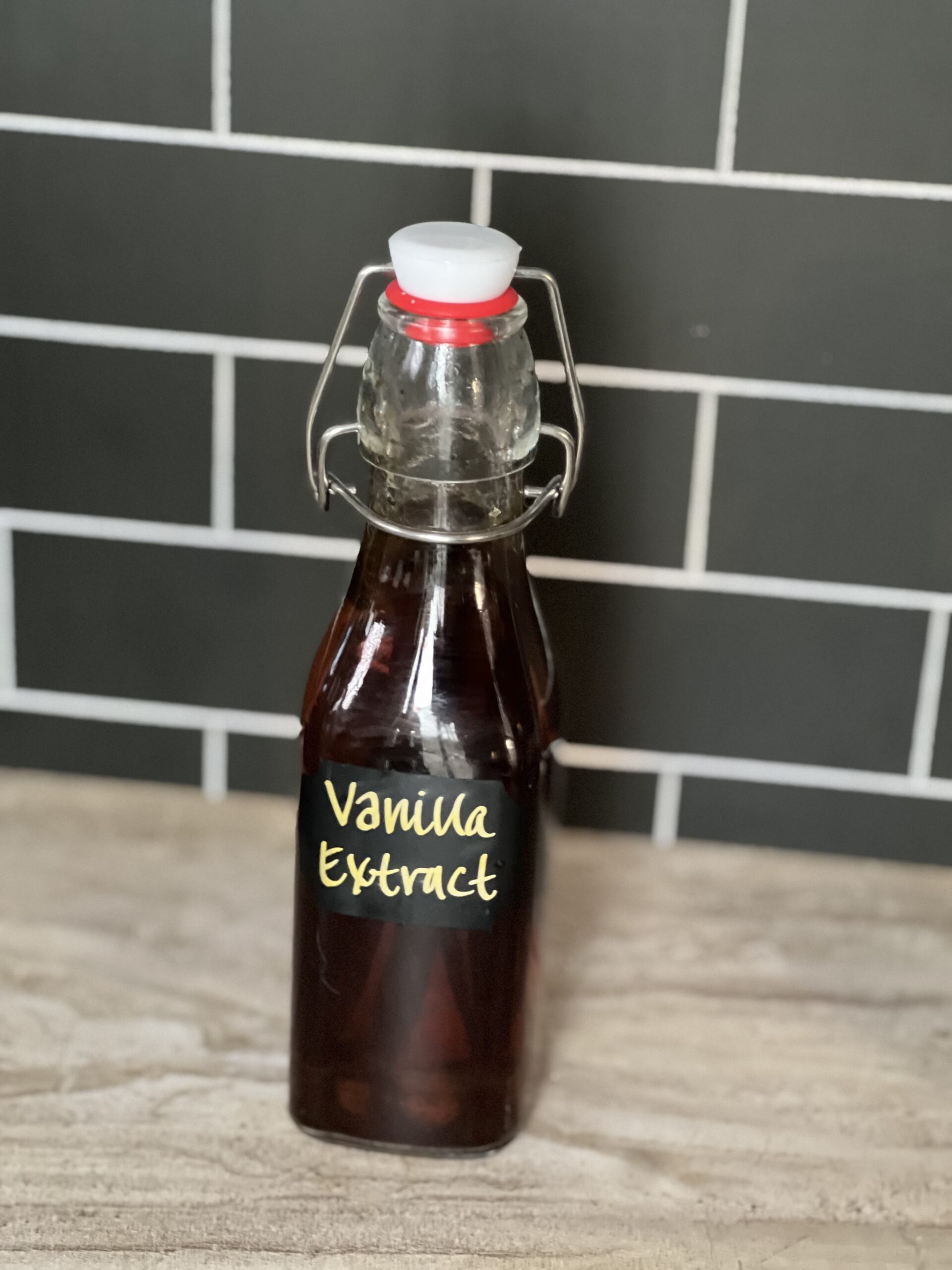 SIngle glass bottle of homemade vanilla extract sitting in kitchen counter