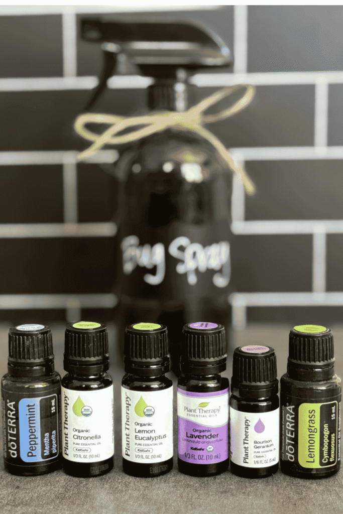 6 essential oils used to make your own bug spray with a homemade bottle of bug spray in a dark glass bottle blurred in the background